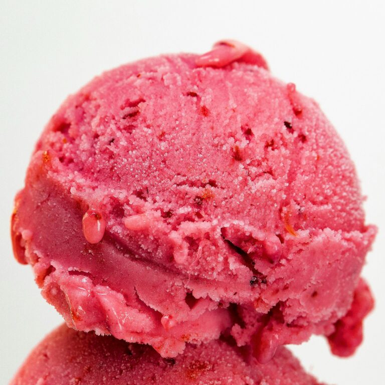 Mouthwatering strawberry ice cream scoop close-up with vibrant pink color and textured details.