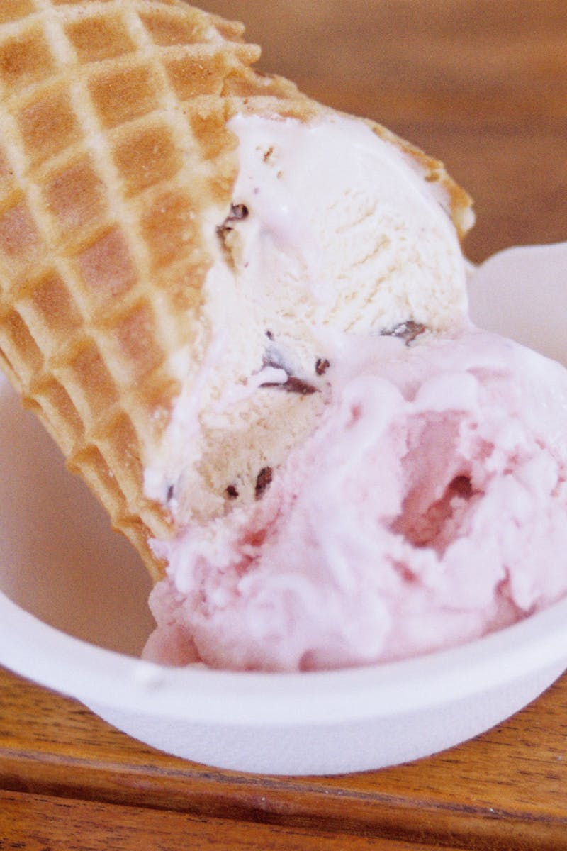 Close-up of a delicious ice cream cone with a waffle texture in a ceramic bowl on a wooden table.